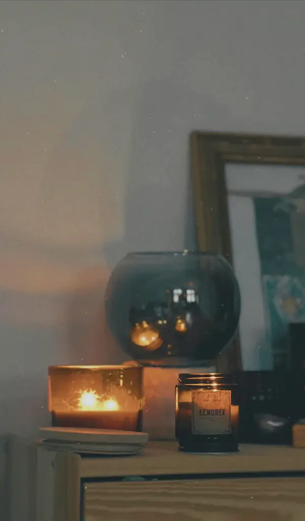 Dekoracyjne świeczki zapachowe ustawione w stylowej aranżacji wnętrza – stolik, sofa i miękkie oświetlenie w tle