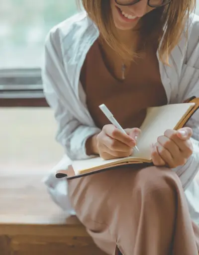 Minimalizm w szafie – kobieta tworzy checklistę kapsułowej garderoby z jeansami, t-shirtami, swetrami i butami w neutralnych kolorach