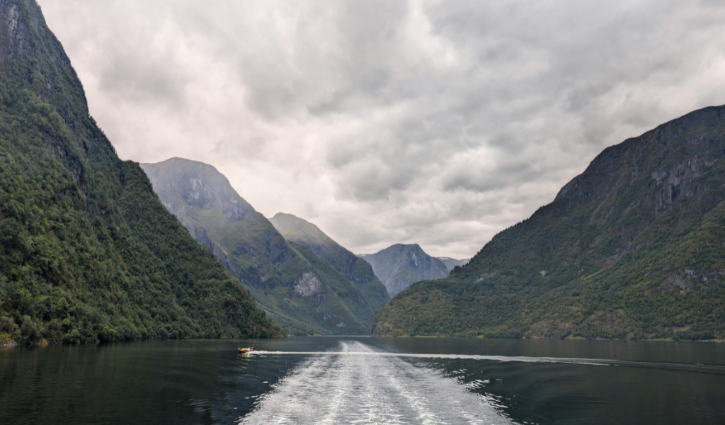 Fiord co to są? Fiordy otoczone stromymi górami, spokojna woda i zachmurzone niebem w tle.