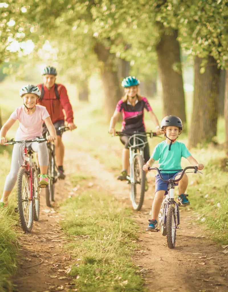 Rodzina jadąca na rowerach podczas majówki, w słoneczny dzień, na tle zielonego krajobrazu