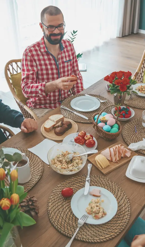 Rodzina przy stole podczas śniadania wielkanocnego, dzieląca się jajkiem i uśmiechami