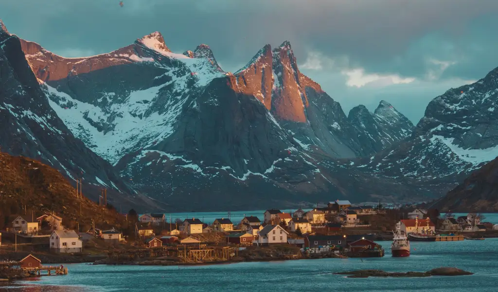 Panoramiczny widok na fiordy i rybacką wioskę Reine na Lofotach, Norwegia – góry odbijające się w spokojnej tafli morza o świcie.