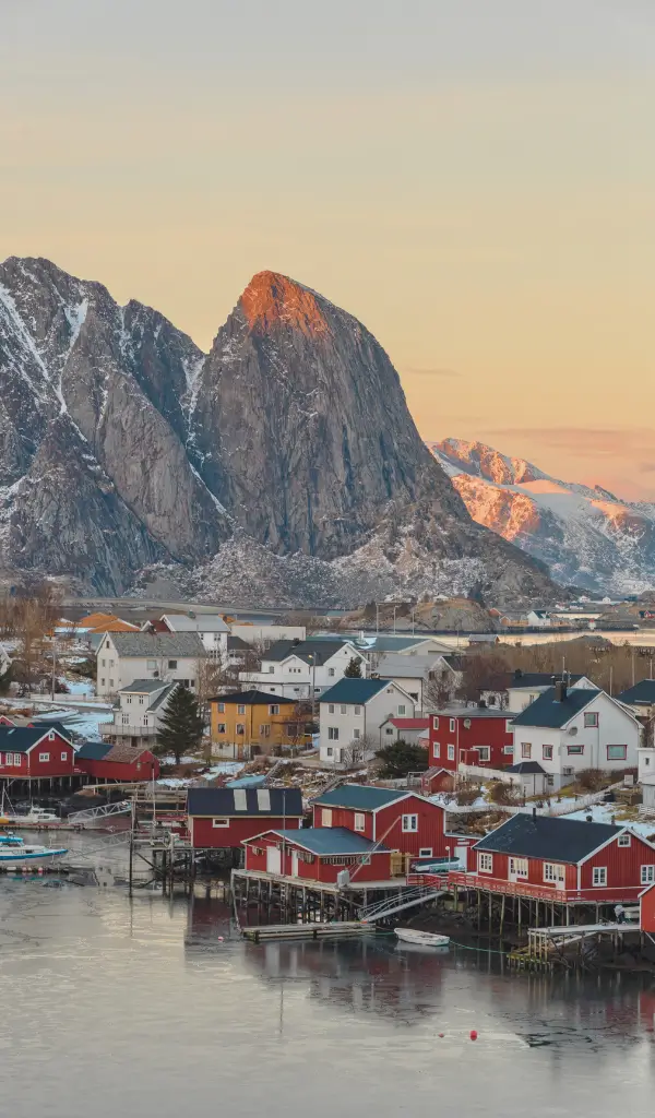 Widok na Reine – malowniczą wioskę rybacką na Lofotach w Norwegii, otoczoną fiordami i górami odbijającymi się w spokojnej wodzie.