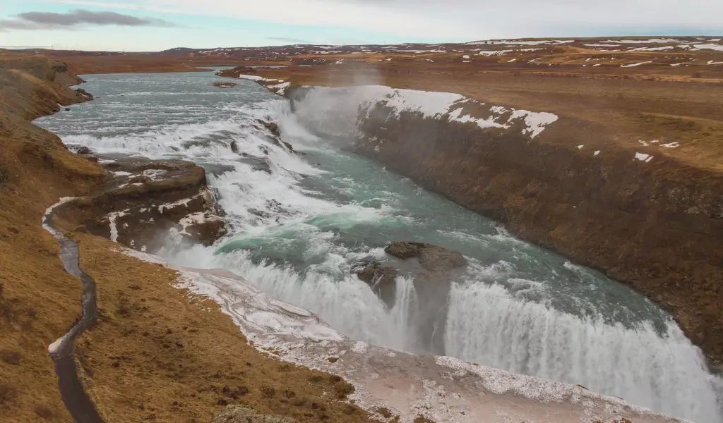 Dwupoziomowy wodospad Gullfoss spadający do głębokiego kanionu, otoczony islandzką przyrodą
