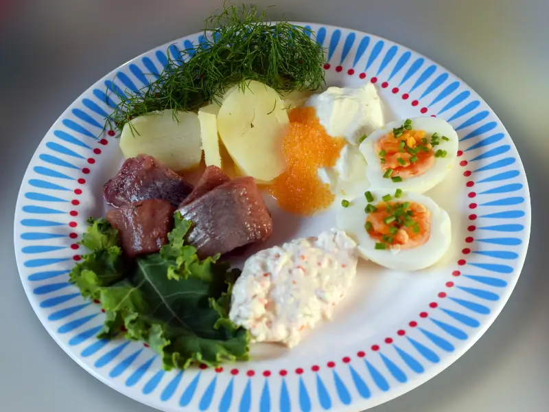 Talerz z klasycznymi potrawami Midsummer: śledź, młode ziemniaki z koperkiem i jajko z kawiorem