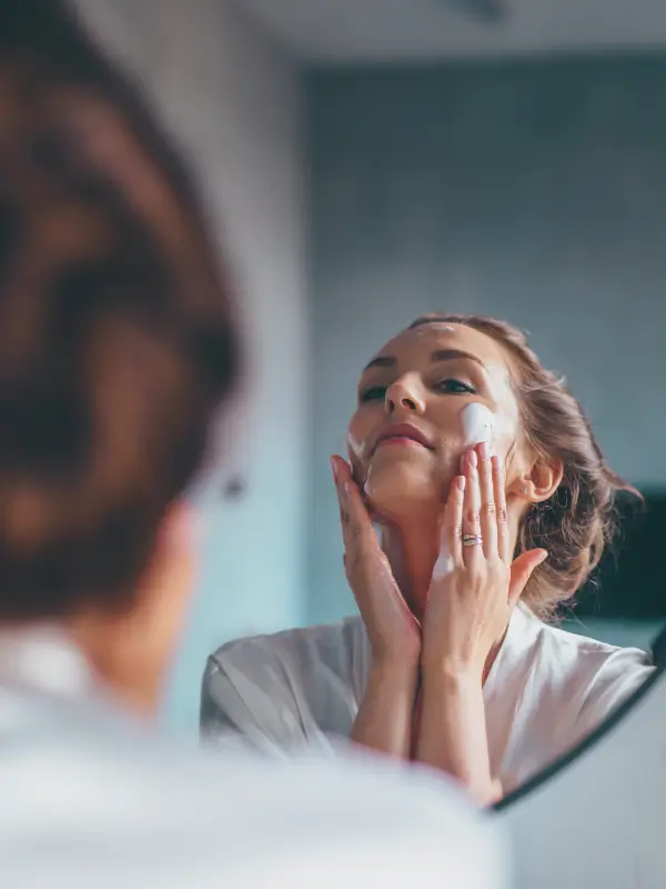 Kobieta nakładająca piankę do oczyszczania twarzy w domowej pielęgnacji