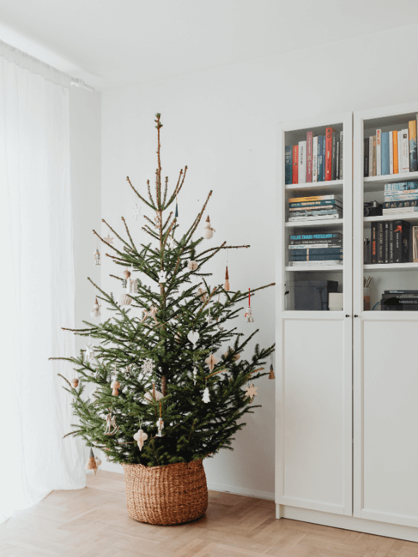 Choinka stojąca w salonie, ozdobiona bombkami i świątecznymi lampkami, tworząca ciepły, bożonarodzeniowy klimat.