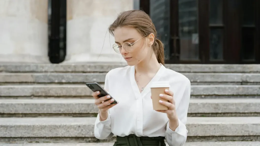Kobieta w okularach trzymająca kubek kawy.