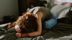 dziewczyna skulona na łóżku zmęczona przebodźcowanie brak energii i napięcie