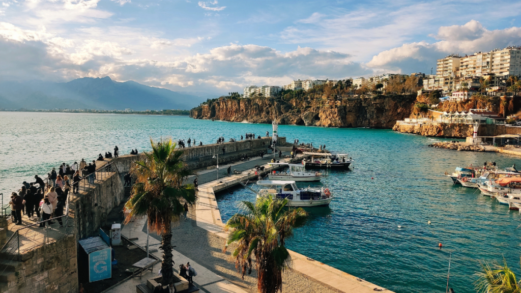 Port i marina w Antalyi w Turcji z jachtami oraz zabytkowym Starym Miastem Kaleiçi w tle.