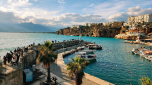 Port i marina w Antalyi w Turcji z jachtami oraz zabytkowym Starym Miastem Kaleiçi w tle.